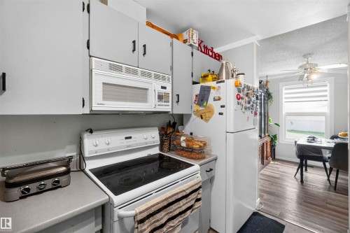 Kitchen featuring white appliances, gray cabinetry with dark hardware, and wood-finish flooring - 17127 109 Street Nw, Edmonton, AB - Indoor Photo Showing Kitchen