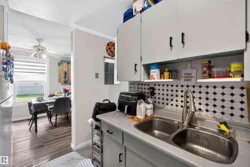 Dual basin stainless steel sink with a high-arc faucet, complemented by a tiled backsplash - 17127 109 Street Nw, Edmonton, AB - Indoor Photo Showing Kitchen With Double Sink