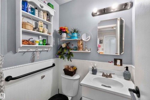 Vanity with integrated sink, wall-mounted mirror, overhead lighting fixture, and wainscoting - 17127 109 Street Nw, Edmonton, AB - Indoor Photo Showing Bathroom