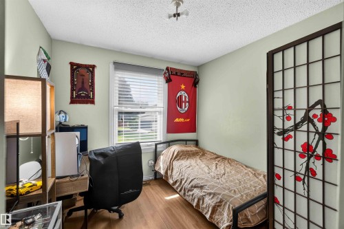 Wood-finish flooring with a window featuring blinds, textured ceiling, and an overhead light fixture - 17127 109 Street Nw, Edmonton, AB - Indoor