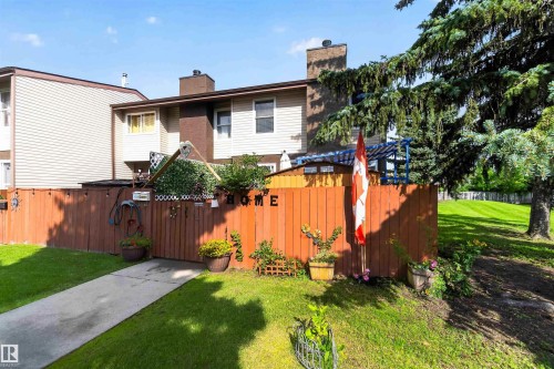 Fenced yard featuring a concrete walkway, mature tree, and adjacent green space - 17127 109 Street Nw, Edmonton, AB - Outdoor