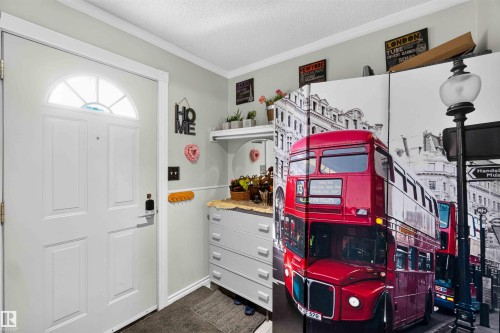 Entryway featuring a white paneled door with an arched transom window, crown molding, and a built-in shelf with a round mirror - 17127 109 Street Nw, Edmonton, AB - Indoor