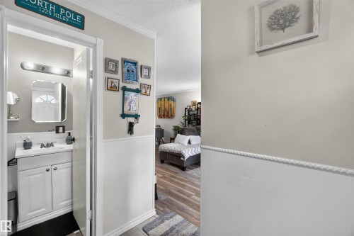 Bathroom featuring a white vanity with built-in cabinetry, an undermount sink, and a framed mirror, complemented by a brushed nickel light fixture - 17127 109 Street Nw, Edmonton, AB - Indoor Photo Showing Bathroom