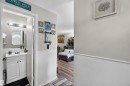 Bathroom featuring a white vanity with built-in cabinetry, an undermount sink, and a framed mirror, complemented by a brushed nickel light fixture - 17127 109 Street Nw, Edmonton, AB  - Indoor Photo Showing Bathroom 