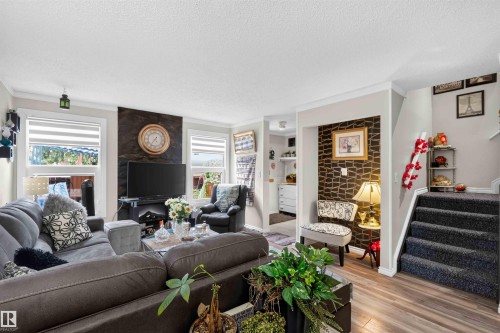 Wood-finish flooring, accent wall with textured finish, contrasting wall decor, built-in shelving, carpeted stairs - 17127 109 Street Nw, Edmonton, AB - Indoor Photo Showing Living Room