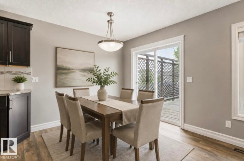 Dark wood-finish cabinetry with silver hardware, light-toned backsplash, and granite-finish countertop - 79 Catalina Crest, Fort Saskatchewan, AB - Indoor Photo Showing Dining Room