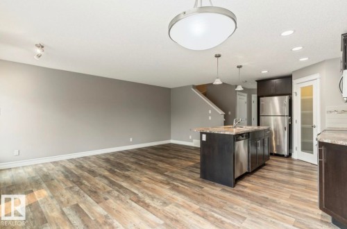 Open-concept living area featuring wood-finish flooring, recessed lighting, and a kitchen island with integrated sink - 79 Catalina Crest, Fort Saskatchewan, AB - Indoor Photo Showing Kitchen