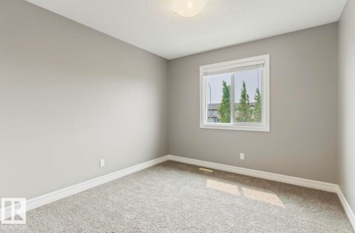 Neutral gray wall paint, white trim, textured carpet, and a large window - 79 Catalina Crest, Fort Saskatchewan, AB - Indoor Photo Showing Other Room