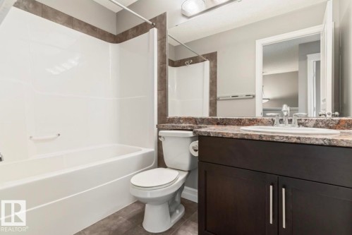 Deep espresso vanity with brushed nickel hardware, complementing a speckled countertop and an undermount sink - 79 Catalina Crest, Fort Saskatchewan, AB - Indoor Photo Showing Bathroom