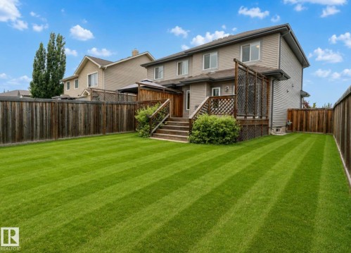 Expansive fenced backyard featuring a manicured lawn, multi-level wooden deck, and mature shrubs - 79 Catalina Crest, Fort Saskatchewan, AB - Outdoor