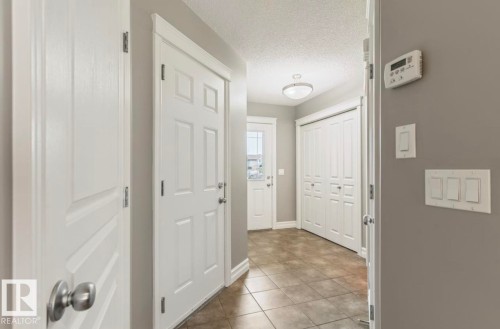 Tiled flooring, white paneled doors, white bi-fold closet doors, contemporary light fixture, and light gray wall paint - 79 Catalina Crest, Fort Saskatchewan, AB - Indoor Photo Showing Other Room
