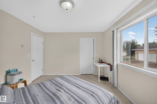 Light-filled interior featuring neutral wall tones and a ceiling-mounted flush light fixture - #105 10421 42 Av Nw, Edmonton, AB - Indoor Photo Showing Bedroom