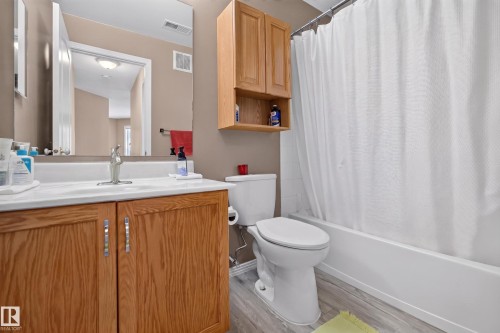 Bathroom featuring a single vanity with wood-finish cabinetry, a white countertop, and a chrome faucet - #105 10421 42 Av Nw, Edmonton, AB - Indoor Photo Showing Bathroom