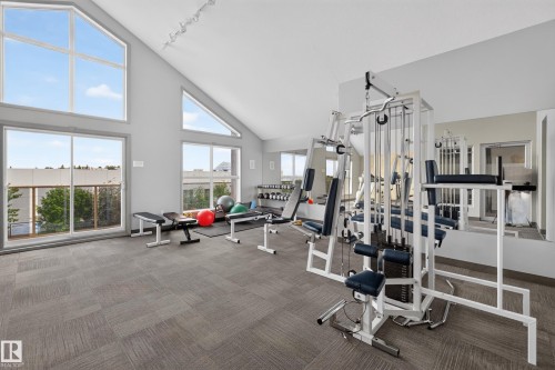 State-of-the-art fitness center featuring floor-to-ceiling windows, professional-grade exercise equipment, wood-finish flooring, and abundant natural light - #105 10421 42 Av Nw, Edmonton, AB - Indoor Photo Showing Gym Room