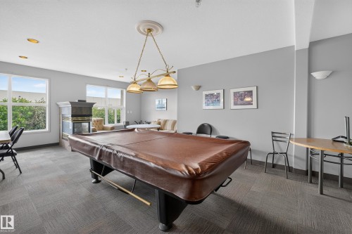 Recreational room featuring a billiards table with a protective cover, a central chandelier, recessed lighting, and large windows - #105 10421 42 Av Nw, Edmonton, AB - Indoor Photo Showing Other Room