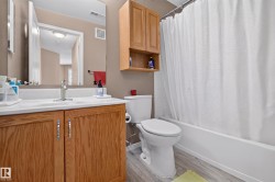 Bathroom featuring a single vanity with wood-finish cabinetry, a white countertop, and a chrome faucet - 