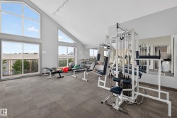 State-of-the-art fitness center featuring floor-to-ceiling windows, professional-grade exercise equipment, wood-finish flooring, and abundant natural light - 