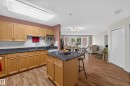 Kitchen featuring wood cabinetry, dark countertops, white subway tile backsplash, and a central island with bar seating - #105 10421 42 Av Nw, Edmonton, AB  - Indoor Photo Showing Living Room 