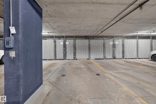 Dedicated storage units within the concrete parking garage, featuring durable chain-link fencing and numbered gates - #105 10421 42 Av Nw, Edmonton, AB - Indoor Photo Showing Garage