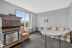 Interior space featuring a large window, a built-in fireplace with a decorative mantel, neutral gray wall paint, recessed lighting, and gray patterned carpet flooring - 