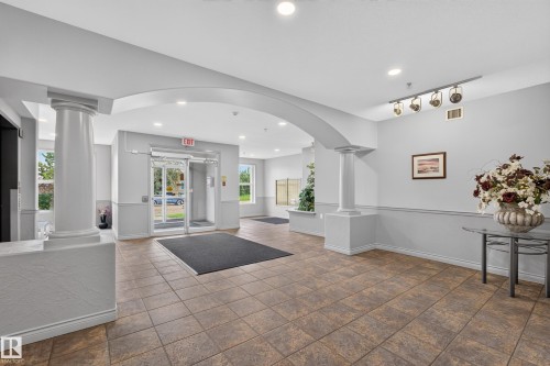 Spacious entryway featuring a tiled floor, architectural columns, an arched doorway, recessed lighting, and large windows - #105 10421 42 Av Nw, Edmonton, AB - Indoor Photo Showing Other Room