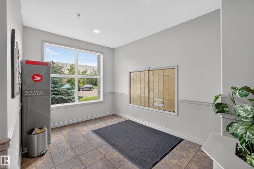 Foyer featuring large grid-pane window, tile flooring, and wainscoting - #105 10421 42 Av Nw, Edmonton, AB - Indoor Photo Showing Other Room