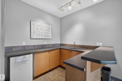 Built-in wet bar featuring a stainless steel sink, dark countertops, and wood-finish cabinetry - 