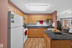 Kitchen featuring wood-finish cabinetry, dark speckled countertops, white subway tile backsplash, and wood-finish flooring - 