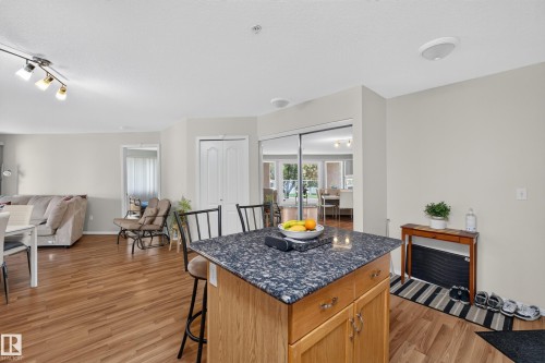 Kitchen island featuring a dark granite-style countertop and wood-finish cabinetry with decorative hardware - #105 10421 42 Av Nw, Edmonton, AB - Indoor
