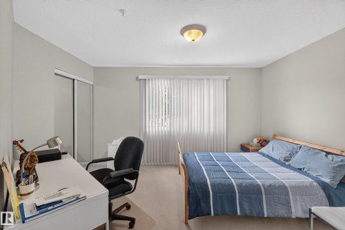 Bedroom featuring light-colored walls, carpet flooring, and a ceiling-mounted light fixture - #105 10421 42 Av Nw, Edmonton, AB - Indoor Photo Showing Bedroom