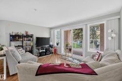Living area with wood-finish flooring, light grey walls, and a large sliding glass door - 