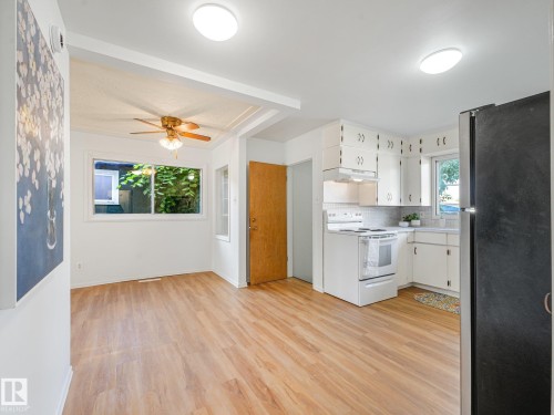 Kitchen with white cabinetry, white electric range, and wood-finish flooring - 6112 105A Street Nw, Edmonton, AB - Indoor Photo Showing Kitchen