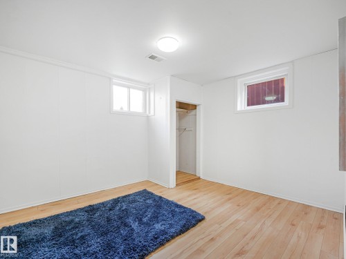 Wood-finish flooring, white paneled walls, two windows, and an open closet with shelving - 6112 105A Street Nw, Edmonton, AB - Indoor Photo Showing Other Room