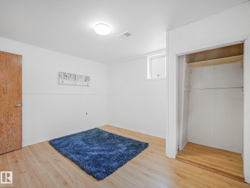 Hardwood flooring, white painted walls, natural wood door, built-in closet with shelving and hanging rod, overhead flush-mount light fixture - 6112 105A Street Nw, Edmonton, AB - Indoor Photo Showing Other Room