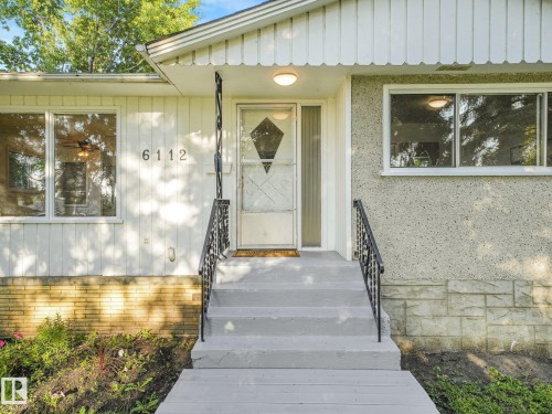 Front entry featuring concrete steps, wrought iron handrails, a covered porch, and exterior lighting - 6112 105A Street Nw, Edmonton, AB - Outdoor