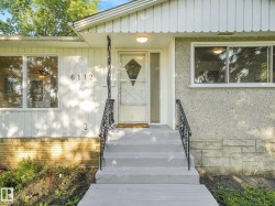 Front entry featuring concrete steps, wrought iron handrails, a covered porch, and exterior lighting - 
