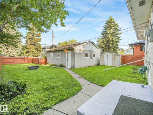 Expansive backyard featuring a concrete patio, established trees, and a detached structure with a concrete pathway - 6112 105A Street Nw, Edmonton, AB - Outdoor
