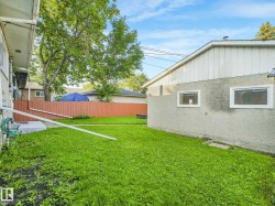 Expansive green space featuring a privacy fence and mature trees - 