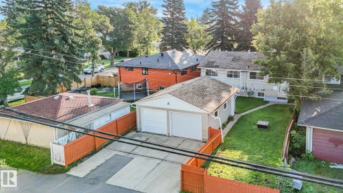 Two-car detached garage with white garage doors, a concrete driveway, and an expansive green lawn - 6112 105A Street Nw, Edmonton, AB - Outdoor