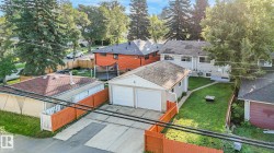Two-car detached garage with white garage doors, a concrete driveway, and an expansive green lawn - 