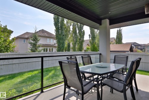 Covered patio with a concrete surface, supported by a substantial column, and enclosed by a glass railing with a dark frame - 3644 Westcliff Way Sw, Edmonton, AB - Outdoor With Deck Patio Veranda With Exterior