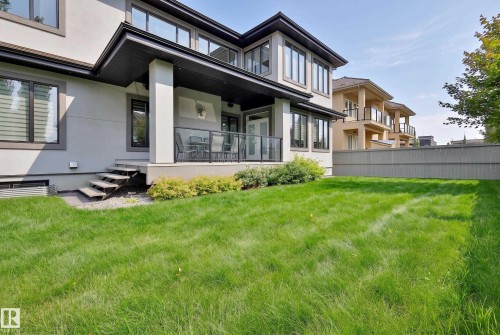 Expansive green lawn with a covered patio, glass railing, and exterior steps - 3644 Westcliff Way Sw, Edmonton, AB - Outdoor With Deck Patio Veranda