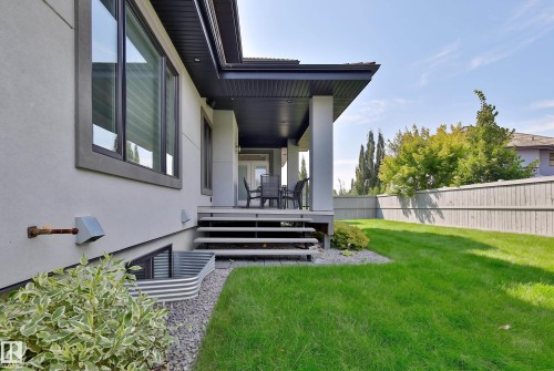 Rear exterior featuring a covered porch, wood deck, and a spacious lawn bordered by a privacy fence - 3644 Westcliff Way Sw, Edmonton, AB - Outdoor