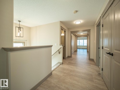 Hallway featuring wood-finish flooring, overhead lighting, neutral wall tones, and trim detailing - 97 Astoria Point(E), Devon, AB - Indoor Photo Showing Other Room