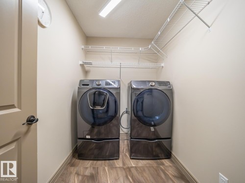 Dedicated laundry area featuring wood-finish flooring, neutral wall paint, overhead lighting, and white wire shelving - 97 Astoria Point(E), Devon, AB - Indoor Photo Showing Laundry Room