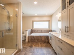 Recessed lighting, glass-enclosed shower, built-in bathtub, dual vanity with undermount sink, and integrated cabinetry - 