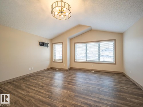 Vaulted ceiling, wood-finish flooring, large windows with blinds, architectural ceiling light fixture, neutral wall color - 97 Astoria Point(E), Devon, AB - Indoor Photo Showing Other Room