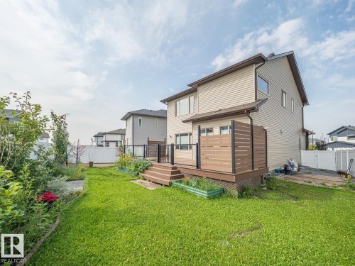 Expansive green lawn with a multi-level deck featuring privacy screening, glass panel railing, and composite decking - 97 Astoria Point(E), Devon, AB - Outdoor