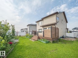 Expansive green lawn with a multi-level deck featuring privacy screening, glass panel railing, and composite decking - 