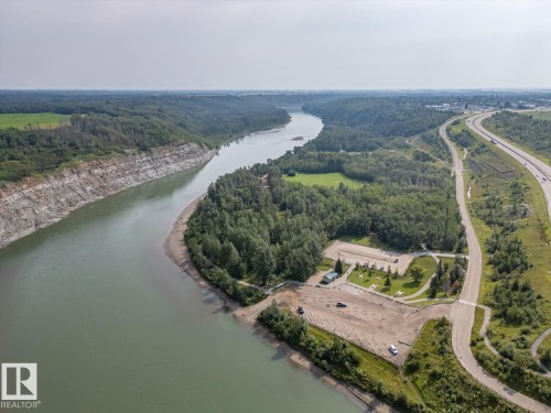 Expansive riverfront property featuring a boat launch, significant tree coverage, paved parking areas, and adjacent highway access - 97 Astoria Point(E), Devon, AB - Outdoor With Body Of Water With View